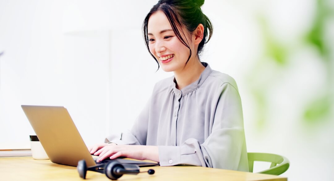 20代女性がパソコンに向かって笑顔で話している